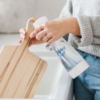 Person using Nellie's Ninety-Nine to remove bacteria on their cutting board in their kitchen