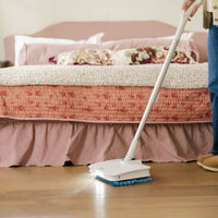 Person cleaning a wooden floor with a mop in a bedroom.
