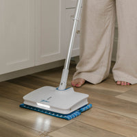 Person using a Wow Too Mop on a wooden floor in a kitchen.