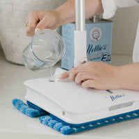 Person pouring Nellie's floor care product with a measuring cup into the Wow Too Mop.