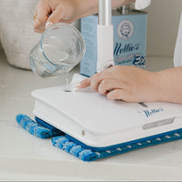 Person refilling their Wow Mop with Nellie's Floor Care and Nellie's Scrub & Polish Pads on the bottom of the mop