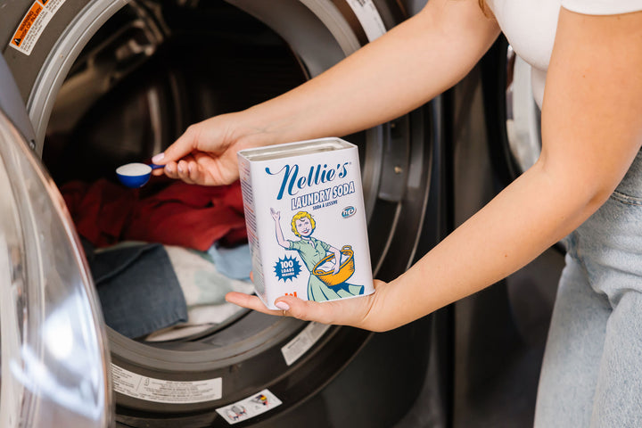 Placing a scoop of Nellie's Laundry Soda in a washing machine.