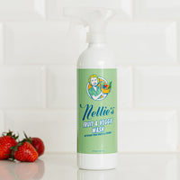 Nellie's Fruit & Veggie Wash on clean kitchen counter with strawberries in the background