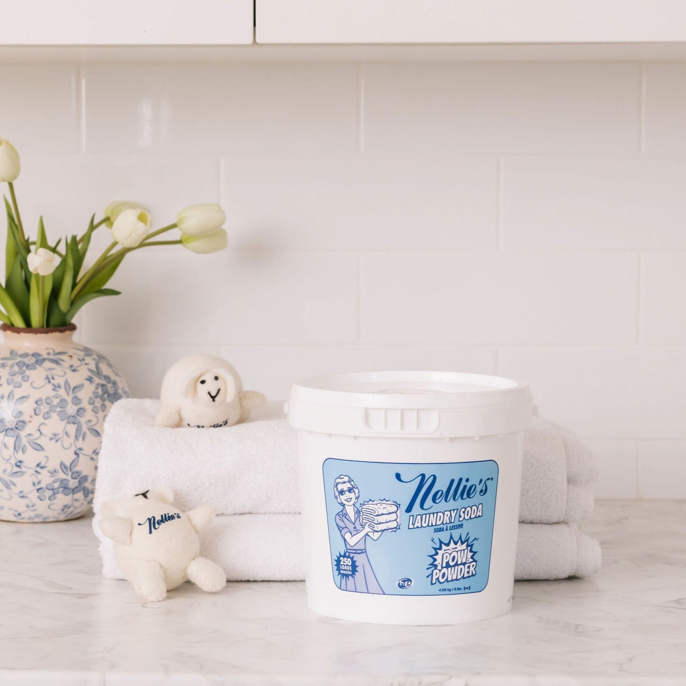 Nellie's Laundry Soda with POW Powder bucket beside towels