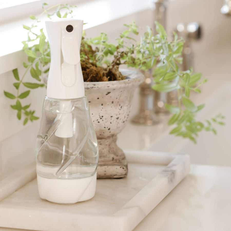 Clear glass reusable spray bottle on kitchen counter