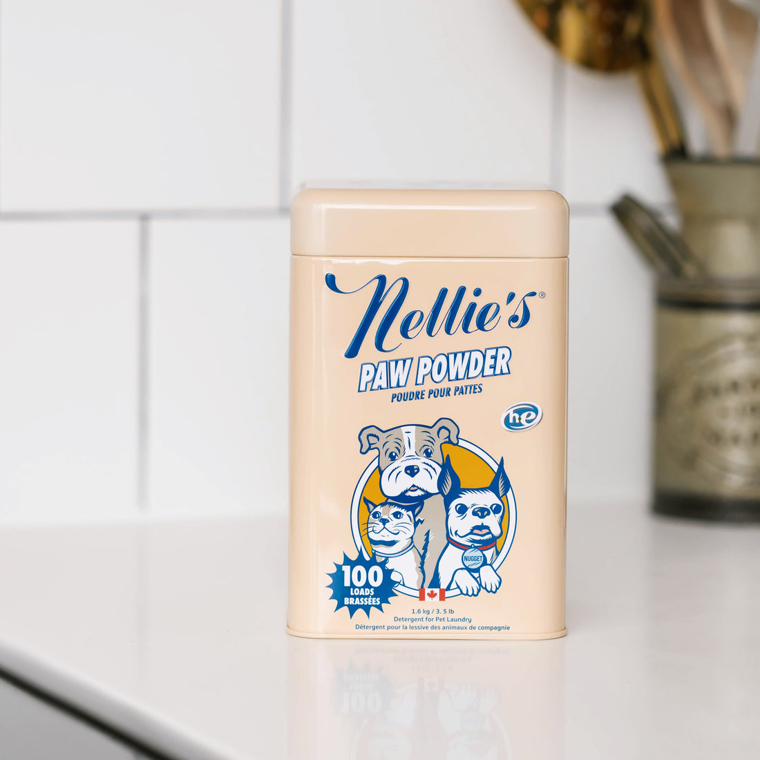 Nellie's Paw Powder container on a kitchen counter with tiled wall and utensils in the background